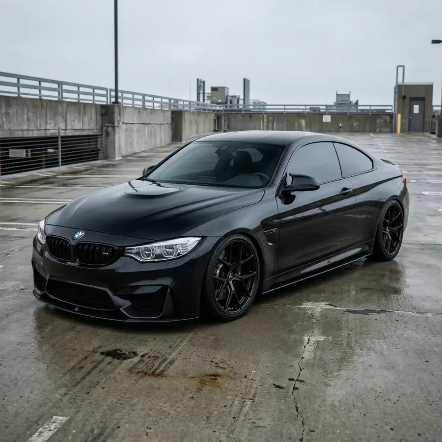 BMW M4 negro con AXYS, estacionamiento mojado